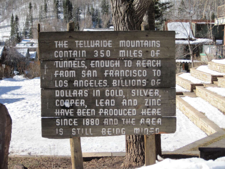 wooden historical sign in Telluride, Colorado describing history of mining in Telluride mountains and San Juan Mountain Range