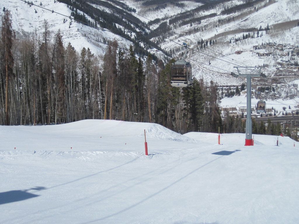 The Eagle Bahn gondola headed up mountain above small terrain park during winter