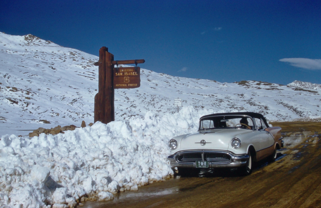 1956 Oldsmobile 98 in orange near Aspen, Colorado in spring time with melting snow