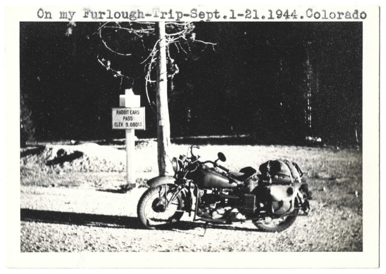 full scan version of 1944 Rabbit Ears Pass Continental Divide sign with motorcycle by soldier on furlough